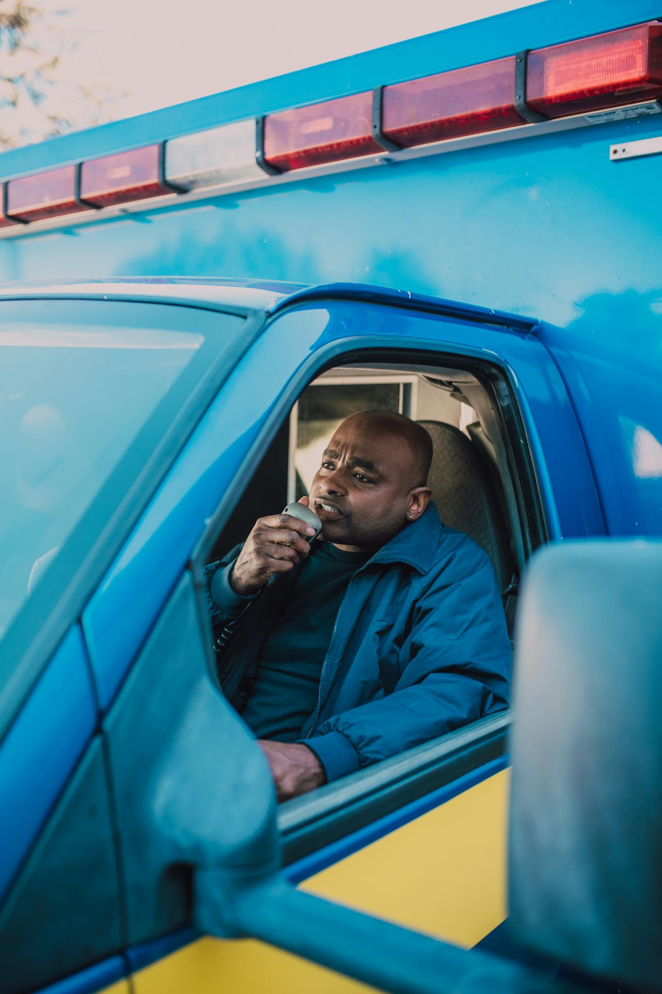 A paramedic in an ambulance talking on a radio, ready to respond to an emergency.