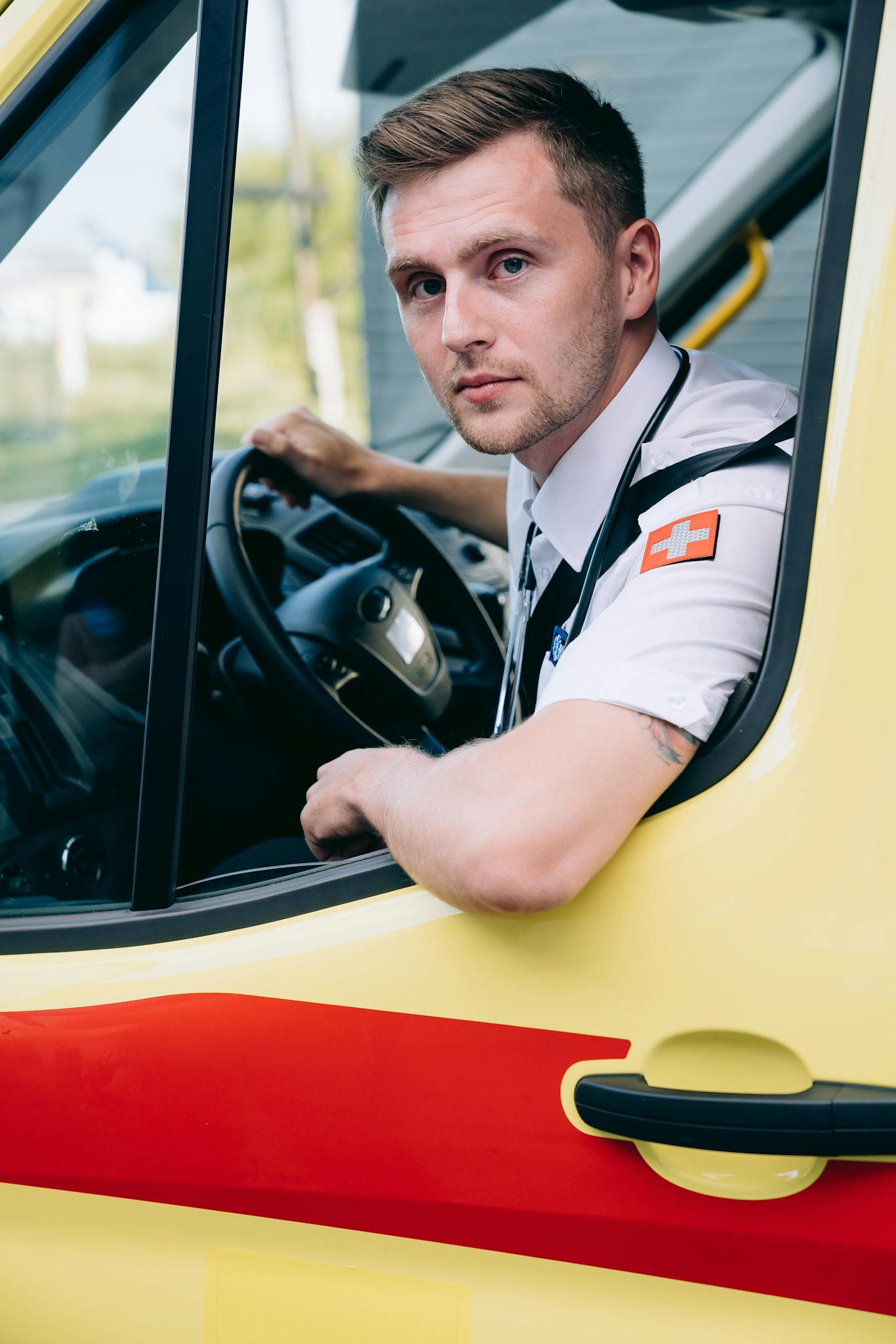 A paramedic in uniform inside an ambulance, ready for an emergency response.