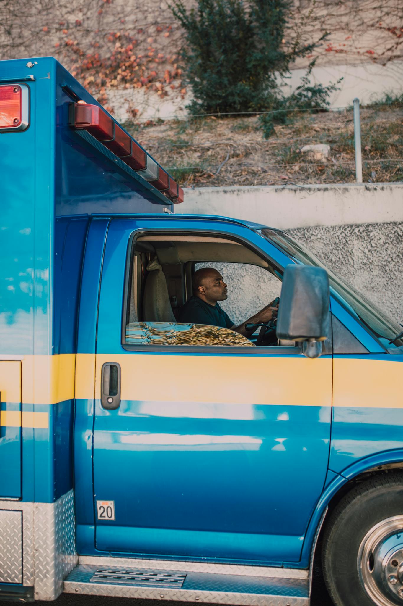Blue ambulance with a paramedic driving, showing emergency vehicle operation.
